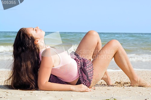 Image of The beauty young woman lies on sand at sea coast