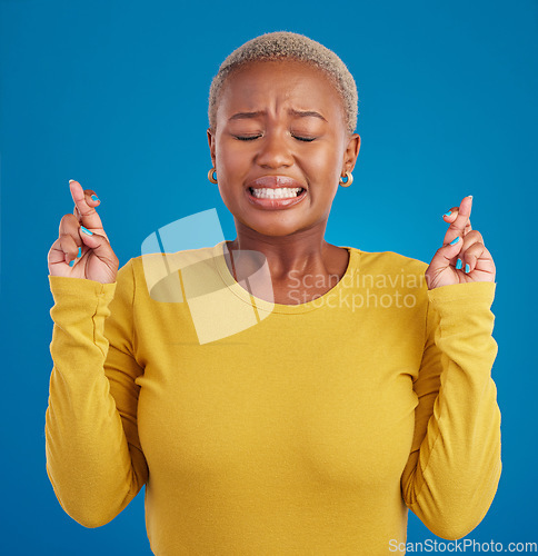 Image of Nervous, fear and fingers crossed by desperate black woman isolated against a studio blue background. Hope, luck and wishing young female doing wish hand gesture worried, miracle and worried