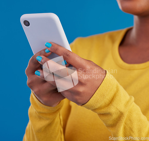 Image of Phone, typing and closeup of hands of woman in studio for social media, text message and browse website. Communication, technology and girl on internet, network and chat online on blue background