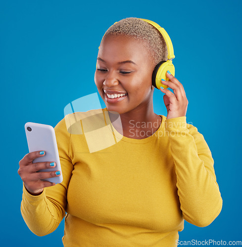 Image of Search, phone and music with black woman in studio for streaming, multimedia and browsing. Gen z, smile and audio with female and headphones on blue background for listening, online radio and songs