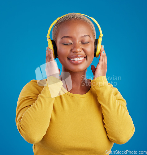 Image of Black woman, face and headphones, listening to music with rhythm and fun with freedom on blue background. Happy female with smile, streaming radio or podcast with peace and eyes closed in studio