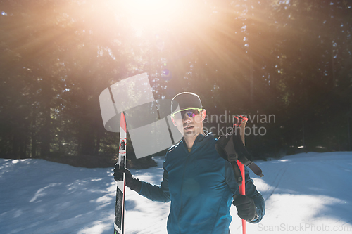 Image of Portrait handsome male athlete with cross country skis in hands and goggles, training in snowy forest. Healthy winter lifestyle concept.