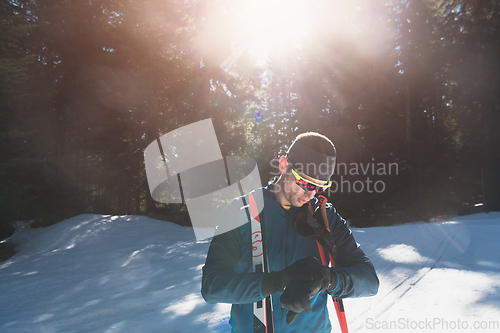 Image of Portrait handsome male athlete with cross country skis in hands and goggles, training in snowy forest. Healthy winter lifestyle concept.