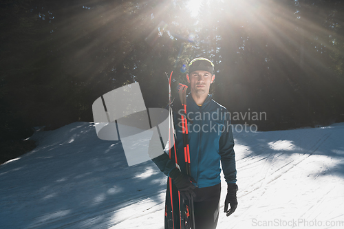 Image of Portrait handsome male athlete with cross country skis in hands and goggles, training in snowy forest. Healthy winter lifestyle concept.