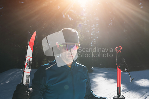 Image of Portrait handsome male athlete with cross country skis in hands and goggles, training in snowy forest. Healthy winter lifestyle concept.