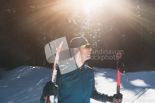 Image of Portrait handsome male athlete with cross country skis in hands and goggles, training in snowy forest. Healthy winter lifestyle concept.