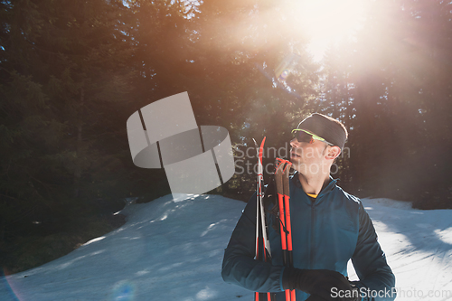 Image of Portrait handsome male athlete with cross country skis in hands and goggles, training in snowy forest. Healthy winter lifestyle concept.