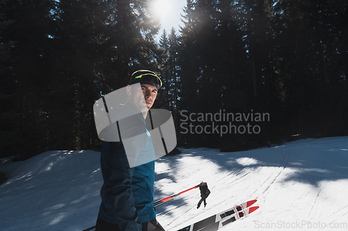 Image of Portrait handsome male athlete with cross country skis in hands and goggles, training in snowy forest. Healthy winter lifestyle concept.