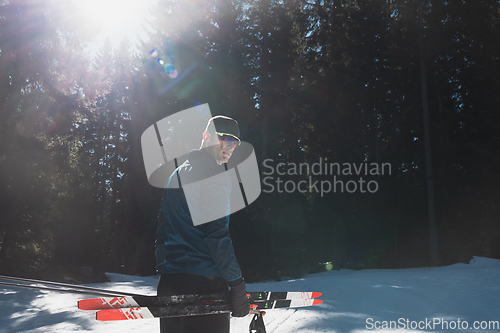 Image of Portrait handsome male athlete with cross country skis in hands and goggles, training in snowy forest. Healthy winter lifestyle concept.