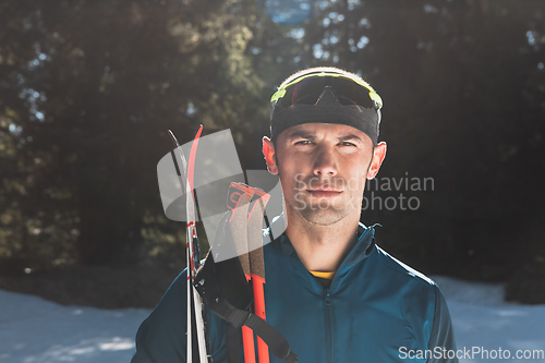 Image of Portrait handsome male athlete with cross country skis in hands and goggles, training in snowy forest. Healthy winter lifestyle concept.