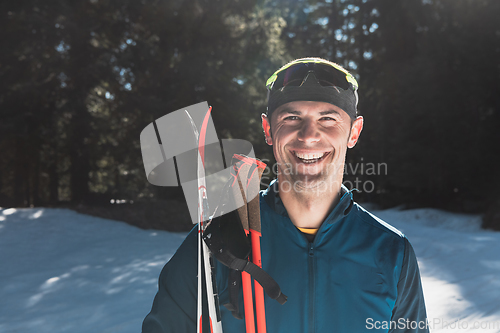 Image of Portrait handsome male athlete with cross country skis in hands and goggles, training in snowy forest. Healthy winter lifestyle concept.