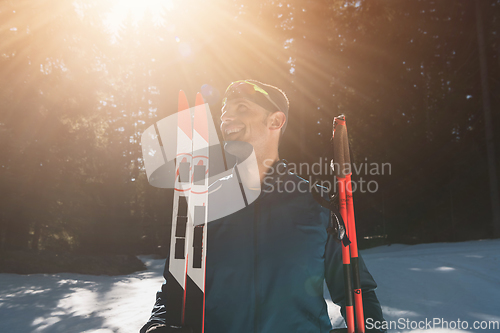 Image of Portrait handsome male athlete with cross country skis in hands and goggles, training in snowy forest. Healthy winter lifestyle concept.