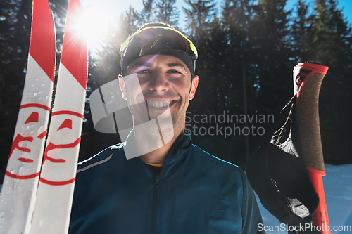 Image of Portrait handsome male athlete with cross country skis in hands and goggles, training in snowy forest. Healthy winter lifestyle concept.