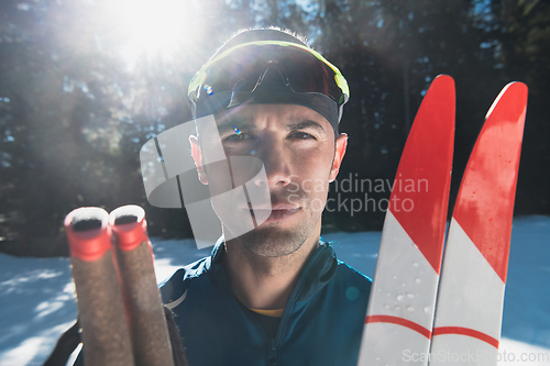 Image of Portrait handsome male athlete with cross country skis in hands and goggles, training in snowy forest. Healthy winter lifestyle concept.