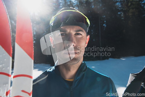 Image of Portrait handsome male athlete with cross country skis in hands and goggles, training in snowy forest. Healthy winter lifestyle concept.