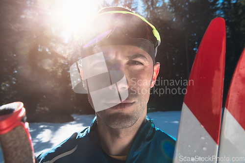 Image of Portrait handsome male athlete with cross country skis in hands and goggles, training in snowy forest. Healthy winter lifestyle concept.