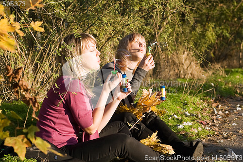 Image of Two beauty young women starts up soap bubble in park