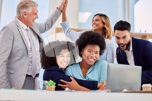 Image of Business people, hugging and high five in congratulations for promotion, sale or bonus at office desk. Women hug in celebration for corporate success, teamwork or support for winning or achievement