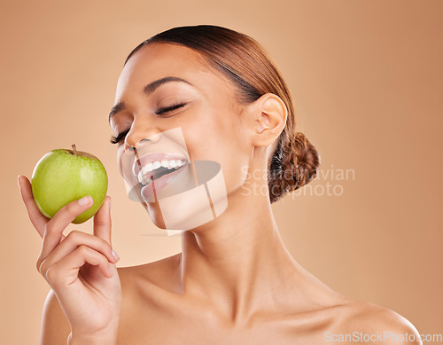 Image of Beauty, skincare and woman with apple, healthy lifestyle and happiness against a brown studio background. Female, lady and fruit for diet, smile and cosmetics with treatment, smooth and soft skin