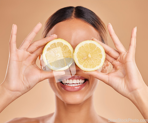 Image of Lemon on eyes, skincare and face of woman with smile in studio for wellness, facial treatment and natural cosmetics. Beauty, spa and happy girl with fruit slice for detox, vitamin c and dermatology