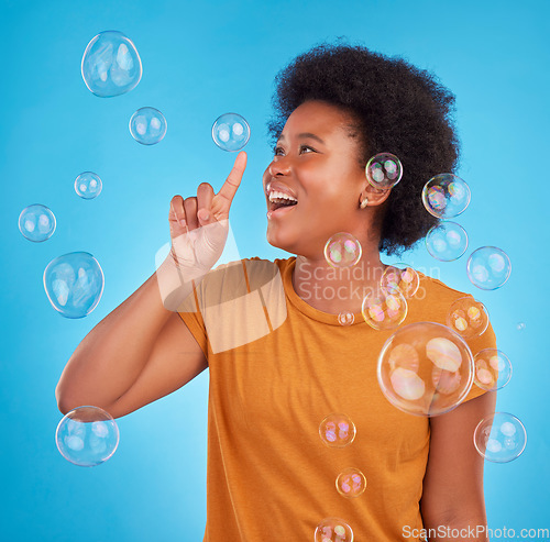 Image of Happy, bubbles and pop with black woman in studio for light, entertainment and satisfaction. Magic, rainbow and creative with female isolated on blue background for burst, happiness and color