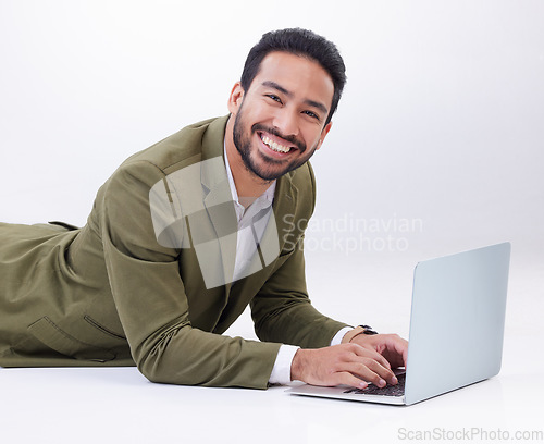 Image of Happy, laptop and portrait of a man in studio relaxing while typing on a keyboard doing research. Happiness, smile and Indian male model with computer working on project isolated by white background.