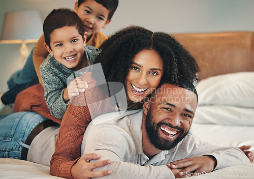 Image of Family, laughing and portrait smile on bed in bedroom, bonding and care in home. Love, interracial and happy mother, comic father and funny children playing, having fun and enjoying time together.