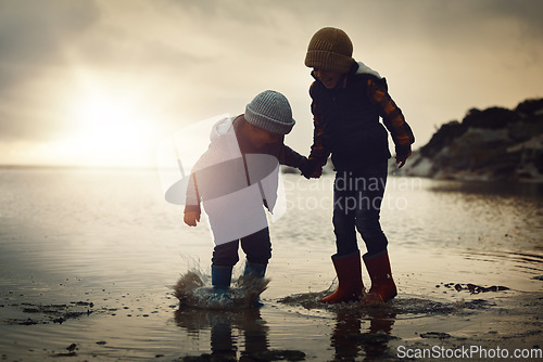 Image of Sunset, silhouette and friends on beach, playing and bonding on summer vacation, break and happiness. Dusk, young people and kids on seaside holiday, brothers and ocean with children, joy or cheerful