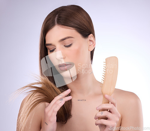 Image of Split ends, hair and woman holding a brush in a isolated, white background and studio. Beauty salon, dye treatment damage and cosmetics of a young female model upset about haircut growth problem