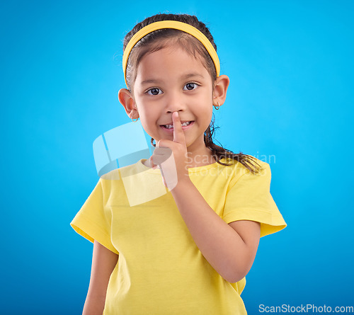 Image of Young girl secret, portrait and studio with a student feeling happy with blue background. Isolated, cute and adorable child face in a yellow outfit with happiness, whisper and cheerful from gossip
