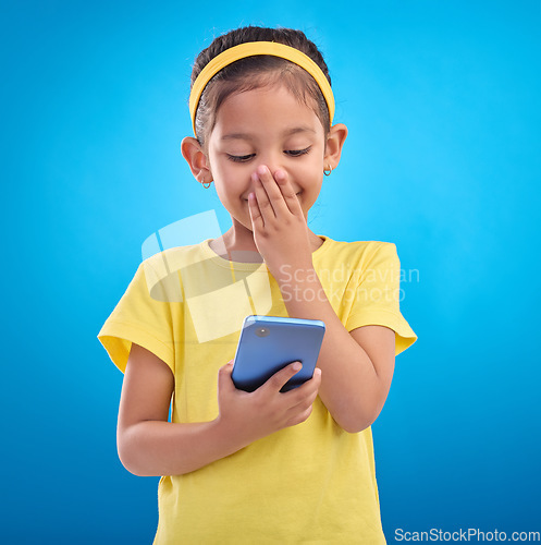 Image of Phone, smile and child laugh on blue background for social media, funny video and internet meme in studio. Technology, communication mockup and happy girl with humor, joke and online on smartphone