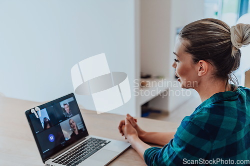 Image of Woman sitting in living room using laptop look at cam talk by video call with business friend relatives, head shot. Job interview answering questions.