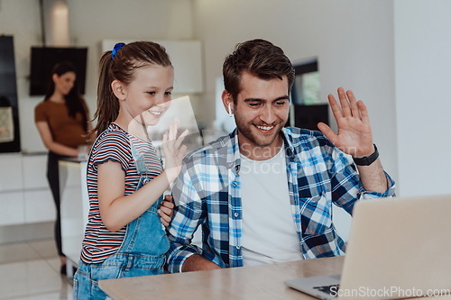 Image of Father and daughter in modern house talking together on laptop with their family during holidays. The life of a modern family