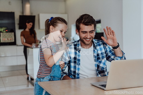 Image of Father and daughter in modern house talking together on laptop with their family during holidays. The life of a modern family