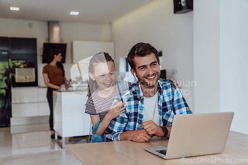 Image of Father and daughter in modern house talking together on laptop with their family during holidays. The life of a modern family