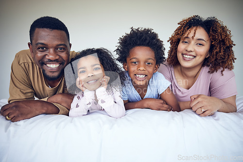 Image of Black family, portrait and relax in bed, happy and smile while bonding in their home together. Face, children and parents waking up in bedroom, lying and resting, having fun and enjoying the weekend