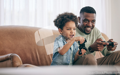 Image of Black family, dad and child playing video games on living room sofa together with controllers at home. Happy African American father with son with smile enjoying bonding time on console entertainment