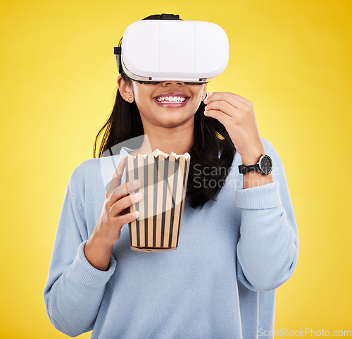 Image of Woman is eating popcorn, happy and VR goggles with snack for watching tv or movie on yellow studio background. Future technology, female with virtual reality experience and corn treat, cinema and UX