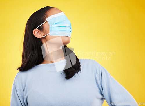Image of Covid, face mask and blindfold with woman in studio for medical, crazy and healthcare. Comic, virus and carefree with female on yellow background for vaccine, protection and pandemic safety