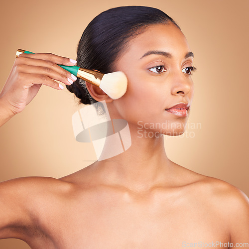 Image of Makeup, product and brush with indian woman in studio for foundation, blush and self care. Glow, cosmetics and facial with female model isolated on brown background for shine, clean and confidence