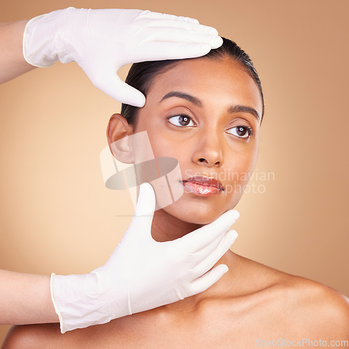 Image of Beauty, plastic surgery and hands with face of Indian woman in studio for cosmetics and skincare. Spa treatment, dermatology and beautician with female on brown background for consulting