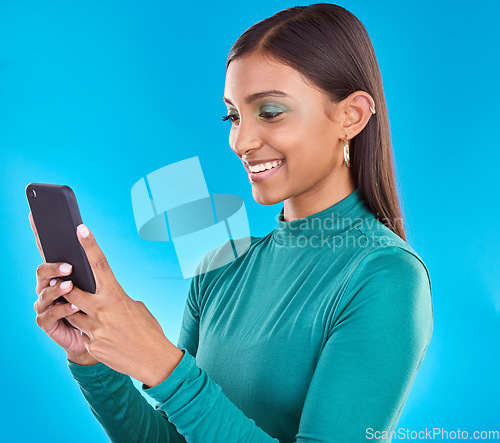 Image of Woman, smile and typing on phone in studio for communication, social media or mobile app. Gen z model person with beauty and smartphone in hands on blue background for network connection or internet