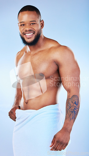 Image of Black man, bodybuilder and towel in studio portrait with smile, wellness or start to morning by blue background. Youth african guy, body and skincare with happiness, health and self care by backdrop