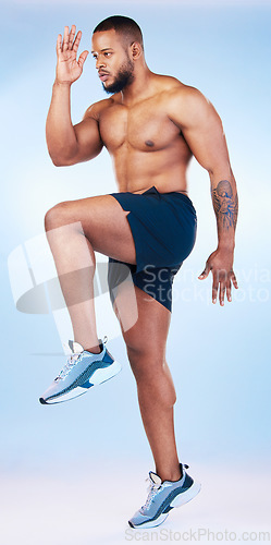 Image of Bodybuilder man, studio and training for running, explosive and balance with focus by blue background. Young fitness expert, body wellness and jumping for strong legs, muscle and health by backdrop