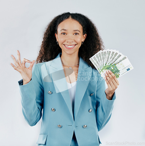 Image of Portrait, happy and cash with a business woman in studio on a gray background making a perfect hand gesture. Face, finance and money with a female employee holding euro bills for investment