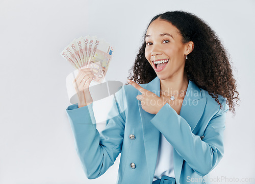 Image of Portrait, pointing and cash with a business woman in studio on a gray background for financial freedom. Smile, finance and money with a happy female employee holding euro bills for investment