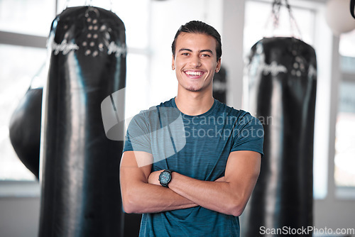 Image of Portrait, boxing and punching bag with a man in the gym, standing arms crossed for fitness or motivation. Happy, exercise and confidence with a handsome young male boxer training for a fight