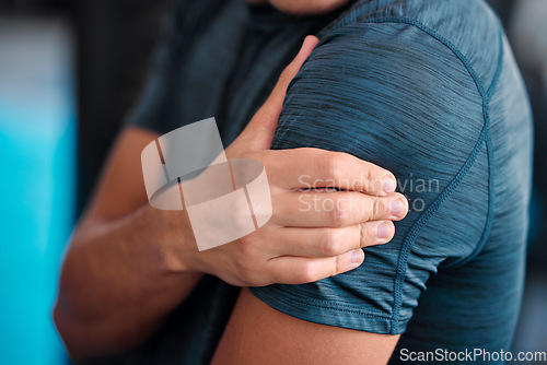 Image of Hand, shoulder and injury with a sports man holding a joint in pain while training in a gym for health. Fitness, accident or anatomy with a male athlete suffering from an injured body during exercise