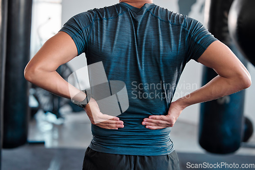 Image of Hands, back pain and injury with a sports man holding a muscle while training in a gym for health. Fitness, accident and anatomy with a male athlete suffering from an injured body during exercise