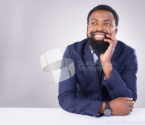 Image of Happy, thinking and a black man sitting by a table isolated on a white background in a studio. Smile, thoughtful and an African businessman with an idea, thought or contemplation on a backdrop